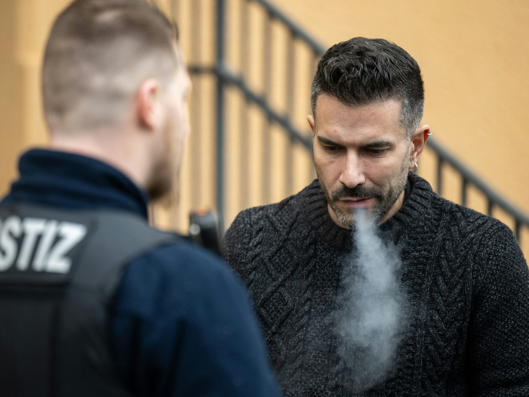 Marc Terenzi (r) raucht neben einem Justizbeamten auf dem Hof des Amtsgerichts Borna.