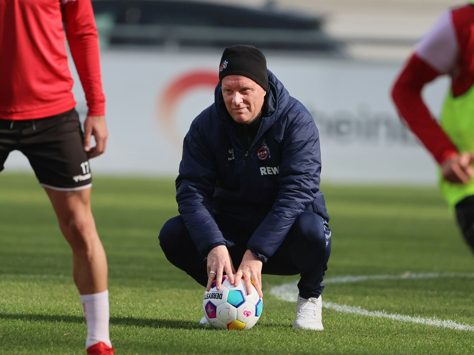 FC-Trainer Timo Schultz hockt auf dem Trainingsplatz, vor ihm liegt ein Ball.