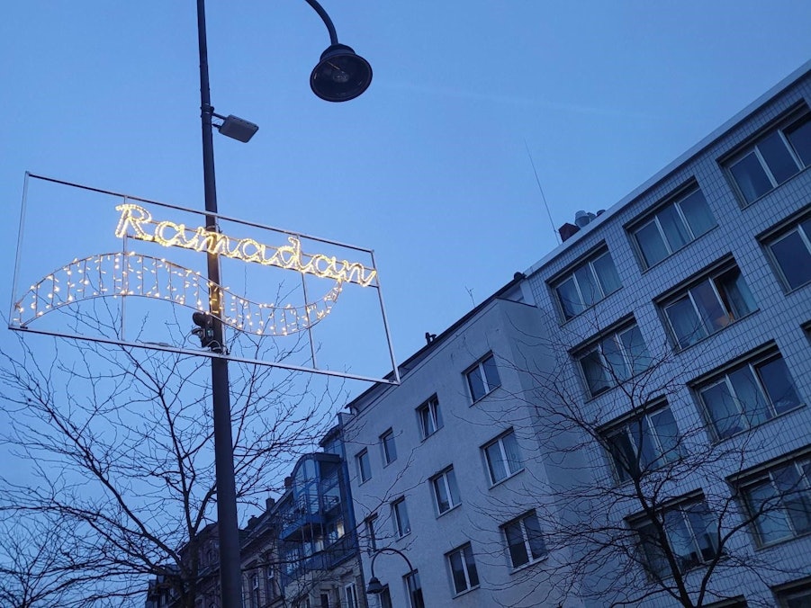 Auf der Venloer Straße fährt ein Auto, am Straßenrand ist die Ramadan-Beleuchtung zu erkennen.