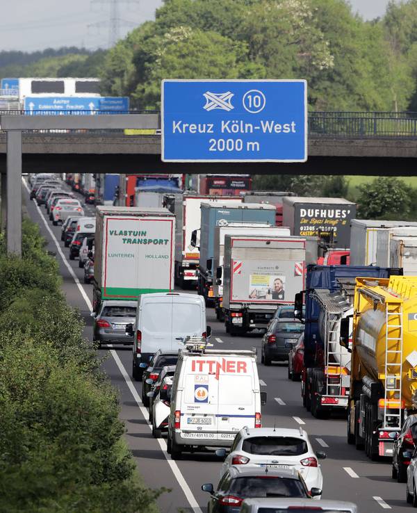Verkehr auf der Autobahn, an einer Brücke hängt ein Schild mit der Aufschrift „Kreuz Köln-West 2000 m“.