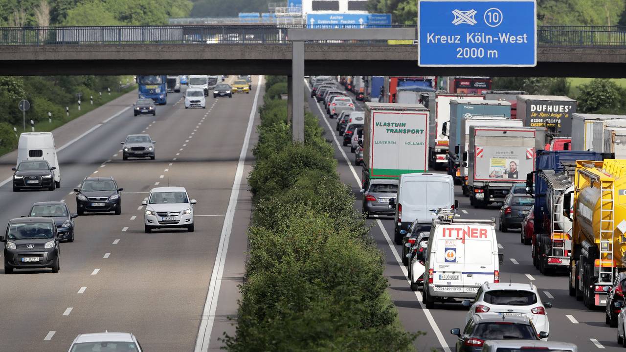 Verkehr auf der Autobahn, an einer Brücke hängt ein Schild mit der Aufschrift „Kreuz Köln-West 2000 m“.