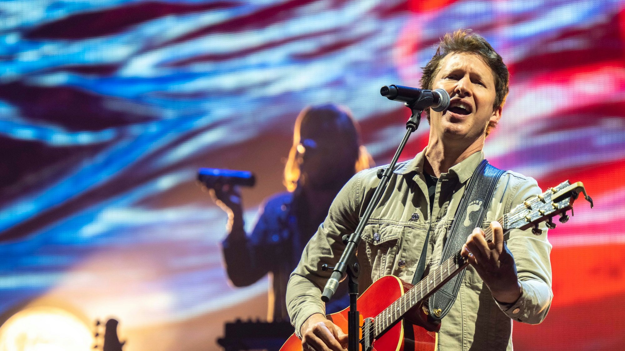 James Blunt steht auf der Bühne und singt.