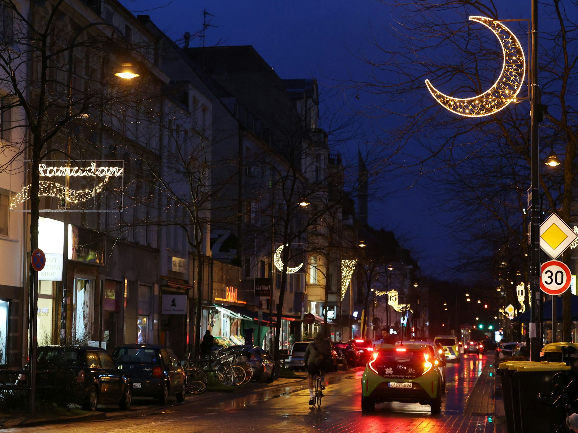 Autos fahren auf der Venloer Straße. Auch die Straßenbeleuchtung ist zu sehen.