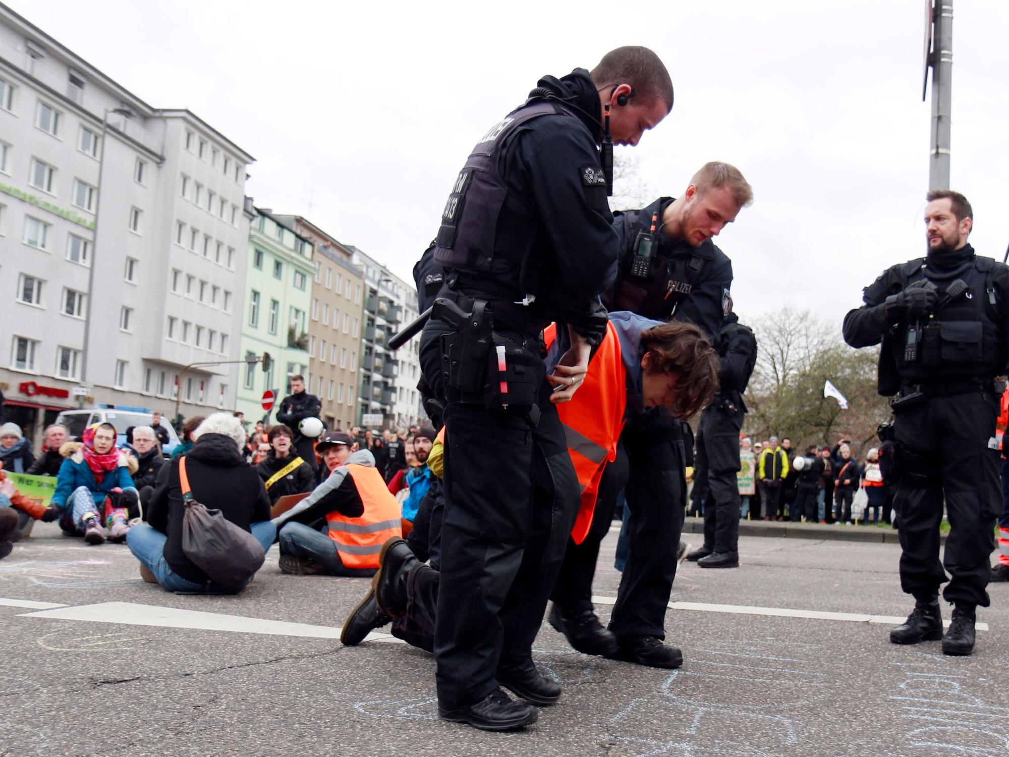Polizisten tragen einen Demonstranten von der Straße.