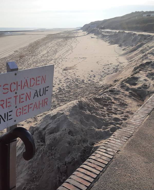 Ein Schild mit der Aufschrift „Flutschäden, Betreten auf eigene Gefahr“ steht am Strand.
