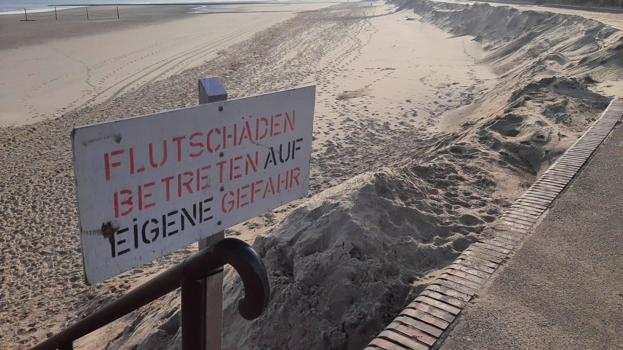 Ein Schild mit der Aufschrift „Flutschäden, Betreten auf eigene Gefahr“ steht am Strand.