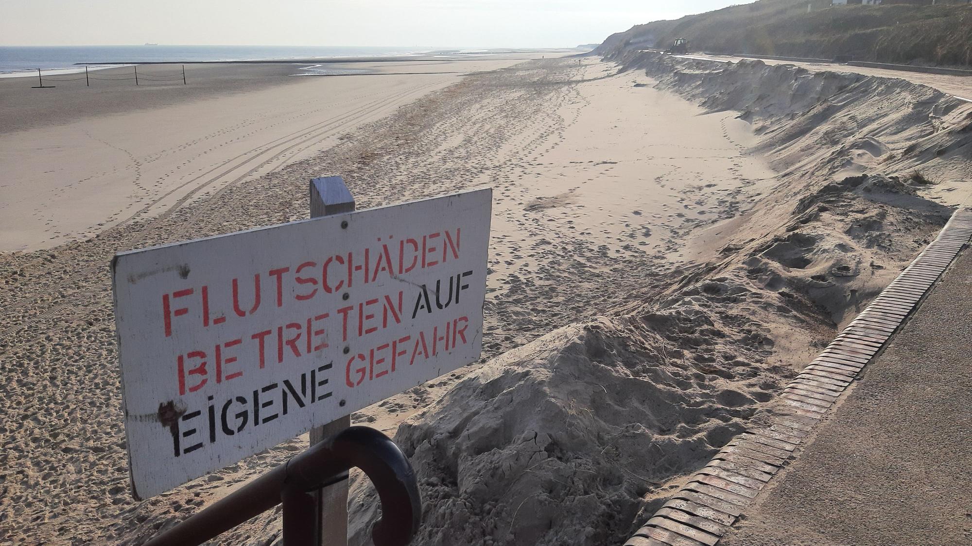 Ein Schild mit der Aufschrift „Flutschäden, Betreten auf eigene Gefahr“ steht am Strand.