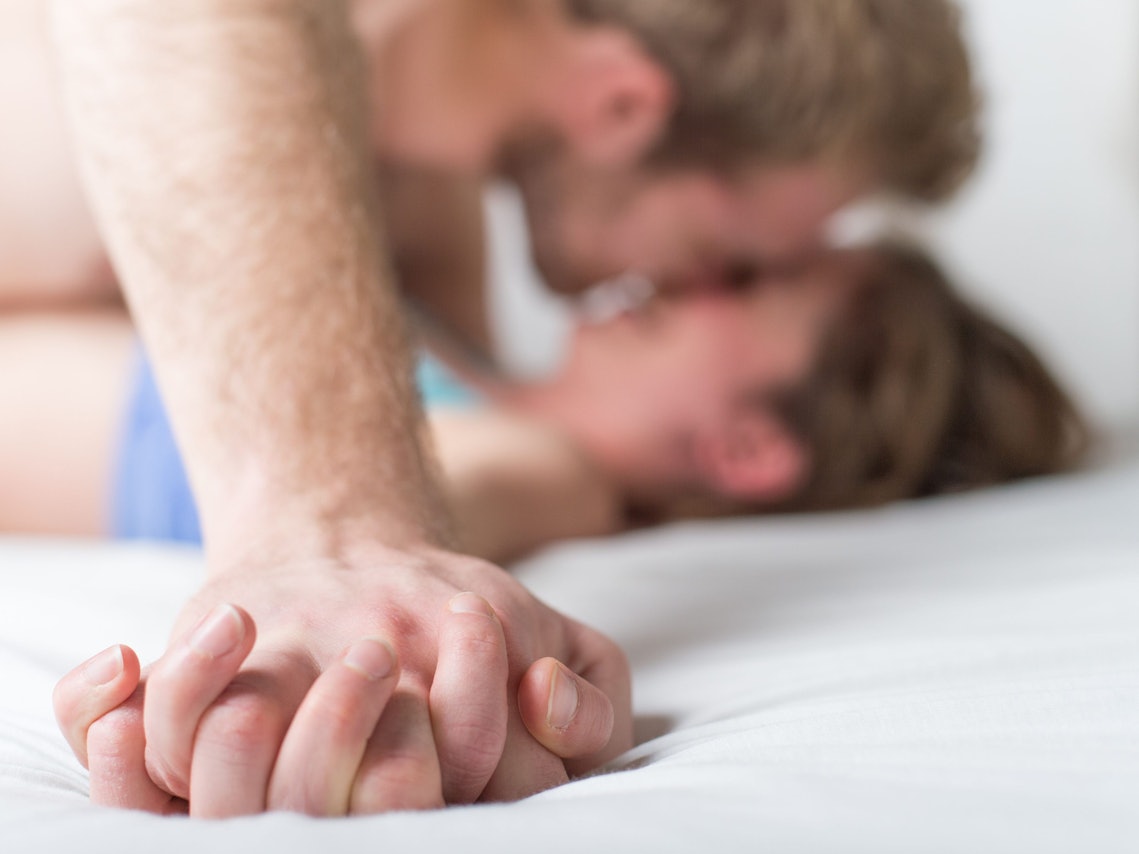 Mann und Frau küssen sich im Bett.