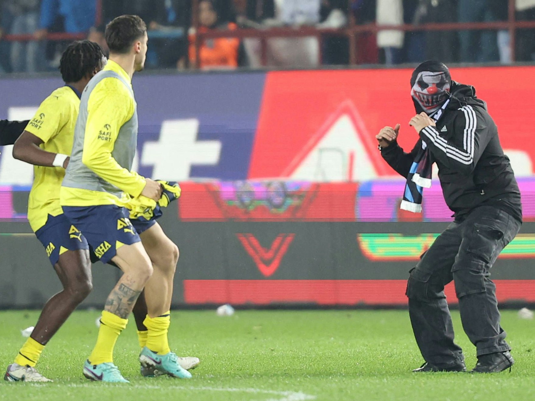 Fenerbahce-Spieler stehen einem vermummten Trabzonspor-Chaoten gegenüber.