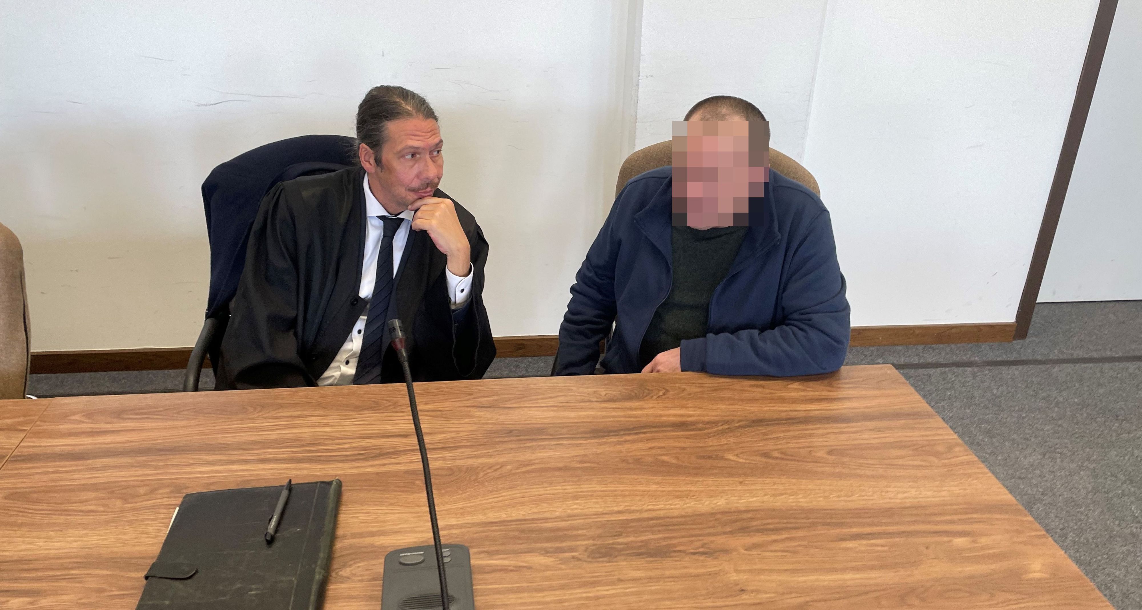 Ein Mann sitzt neben seinem Anwalt auf der Anklagebank,