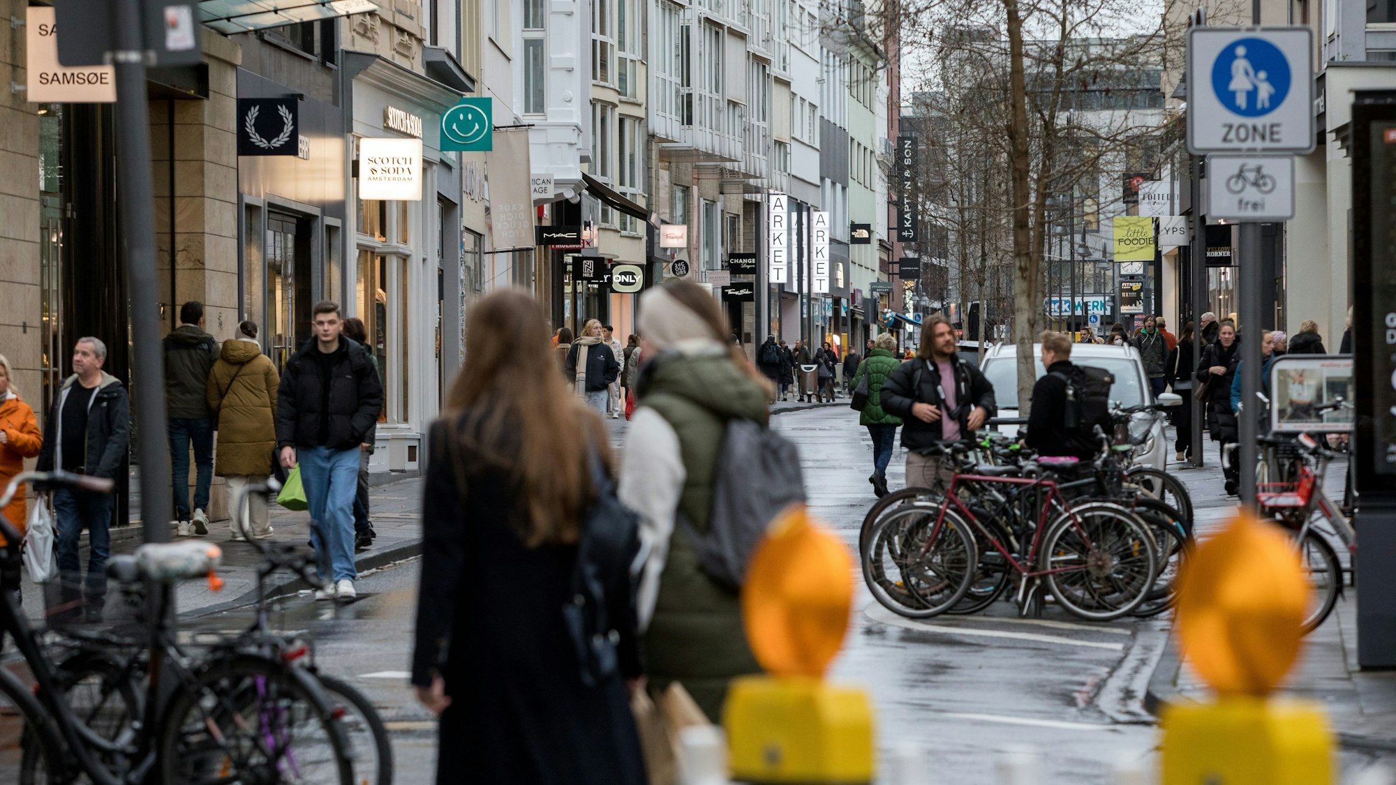 Menschen sind auf der Ehrenstraße unterwegs. Ein Schild zeigt an, dass es sich um eine Fußgängerzone handelt.