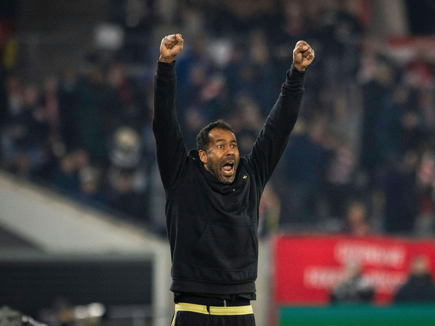 Daniel Thioune streckt die Arme in die Luft und jubelt.