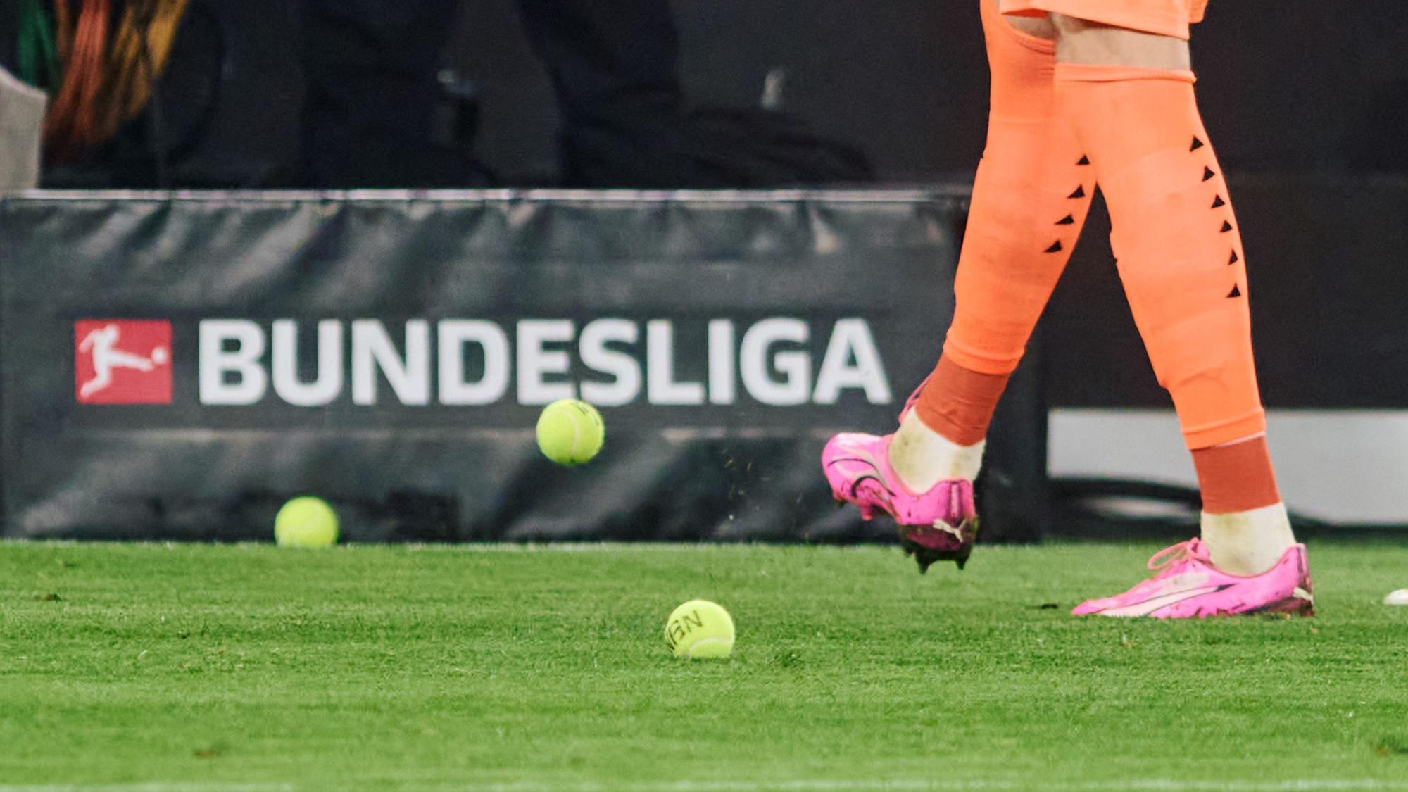 Mehrere Tennisbälle fliegen auf das Spielfeld.