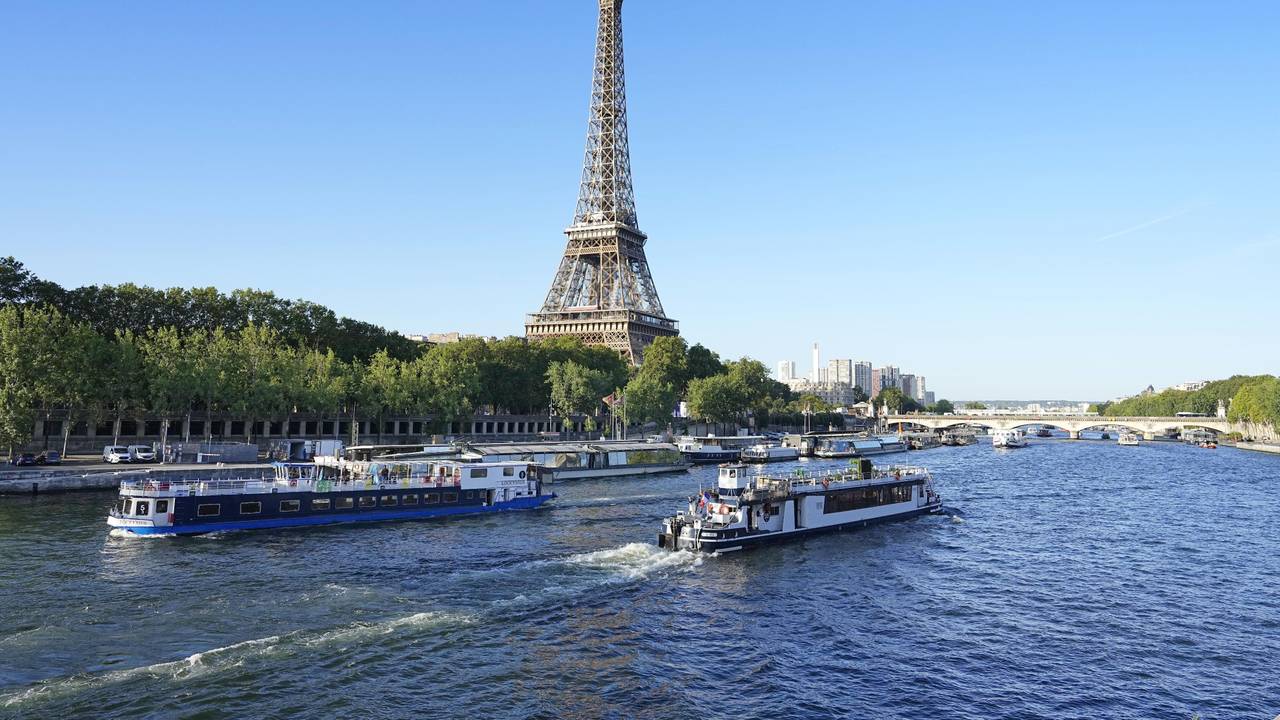 Ein Boot und ein Lastkahn fahren vor dem Eiffelturm auf der Seine während eines Tests für die Eröffnungsfeier der Olympischen Spiele 2024 in Paris. Für die Eröffnungsfeier der Spiele am 26. Juli 2024 sind Tausende von Olympioniken auf rund 160 Booten auf dem Fluss geplant.