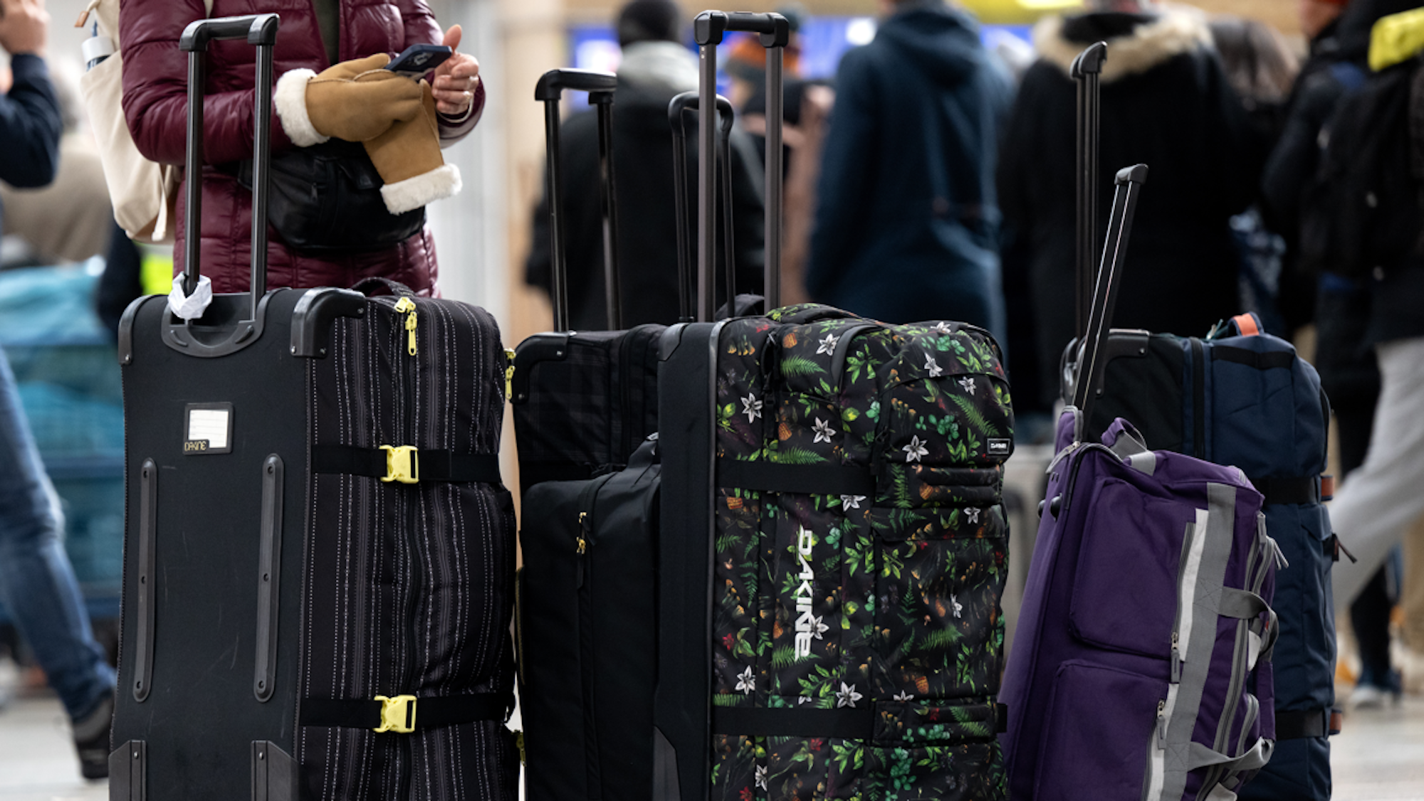 Menschen stehen mit Koffern am Bahnhof und warten.