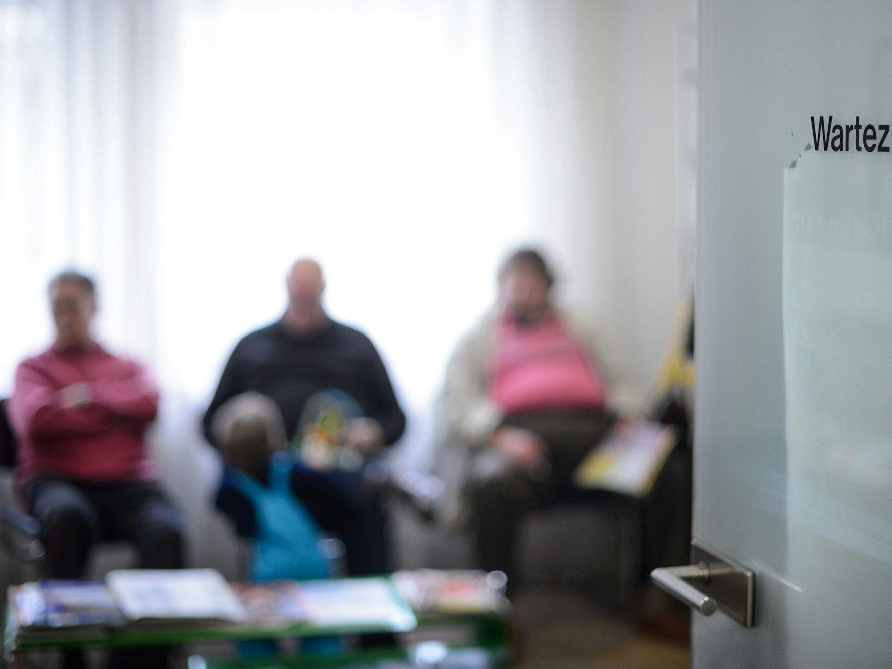 Patienten und Patientinnen warten im Wartezimmer einer Arztpraxis.
