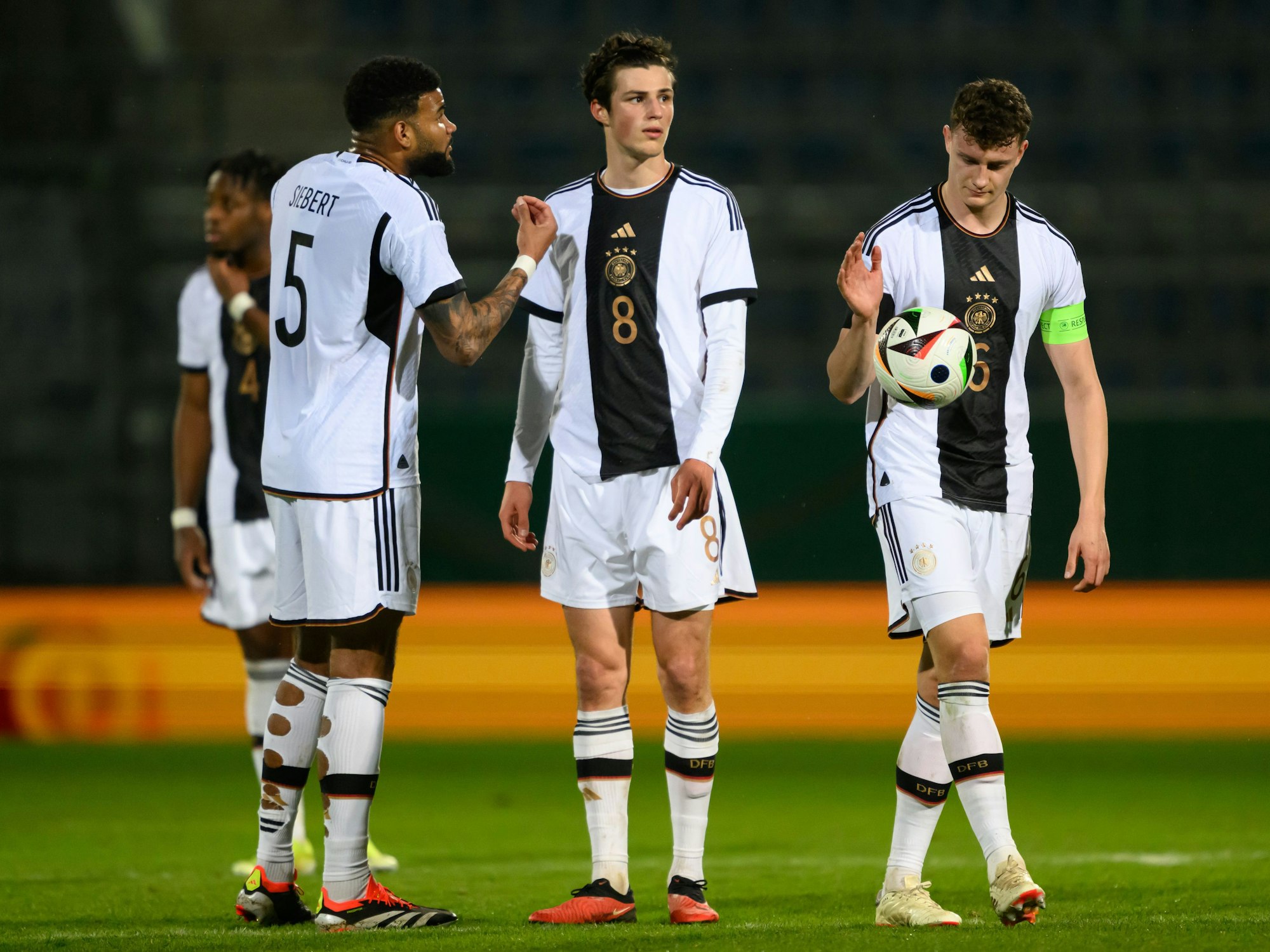 Deutschlands Jamil Siebert, Merlin Röhl und Eric Martel stehen auf dem Feld.