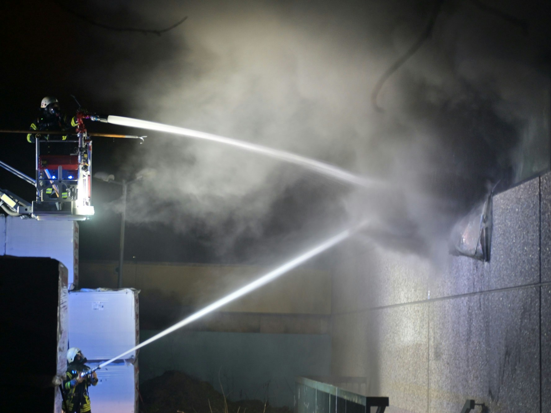 Die Feuerwehr löscht ein Gebäude, aus dem es qualmt.