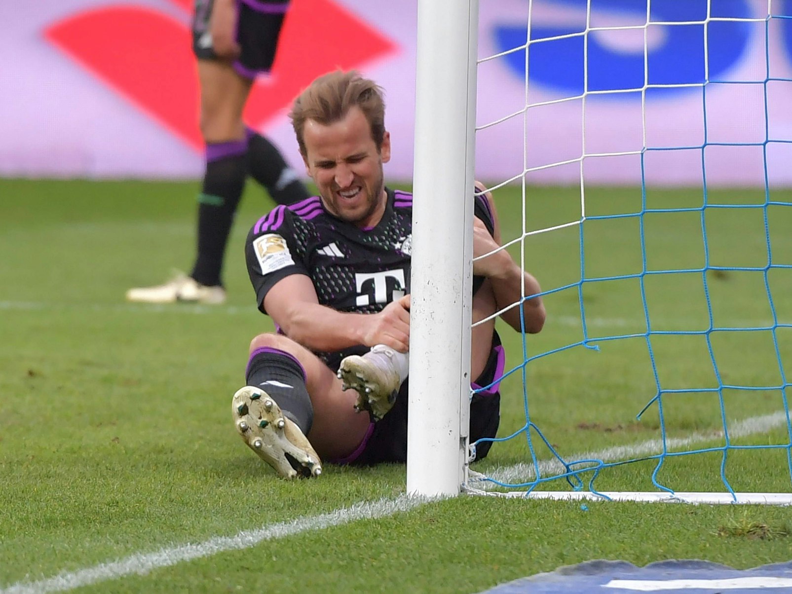 Harry Kane hält sich mit schmerzverzerrtem Gesicht das Bein.