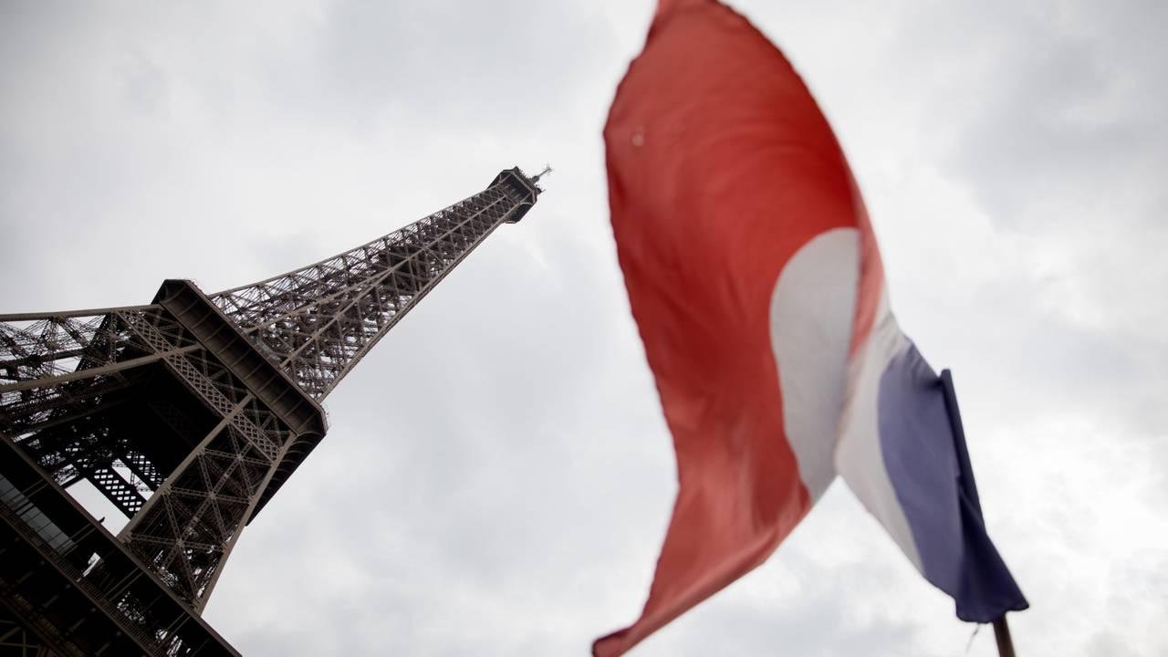 Die französische Trikolore weht vor dem Eiffelturm im Wind.