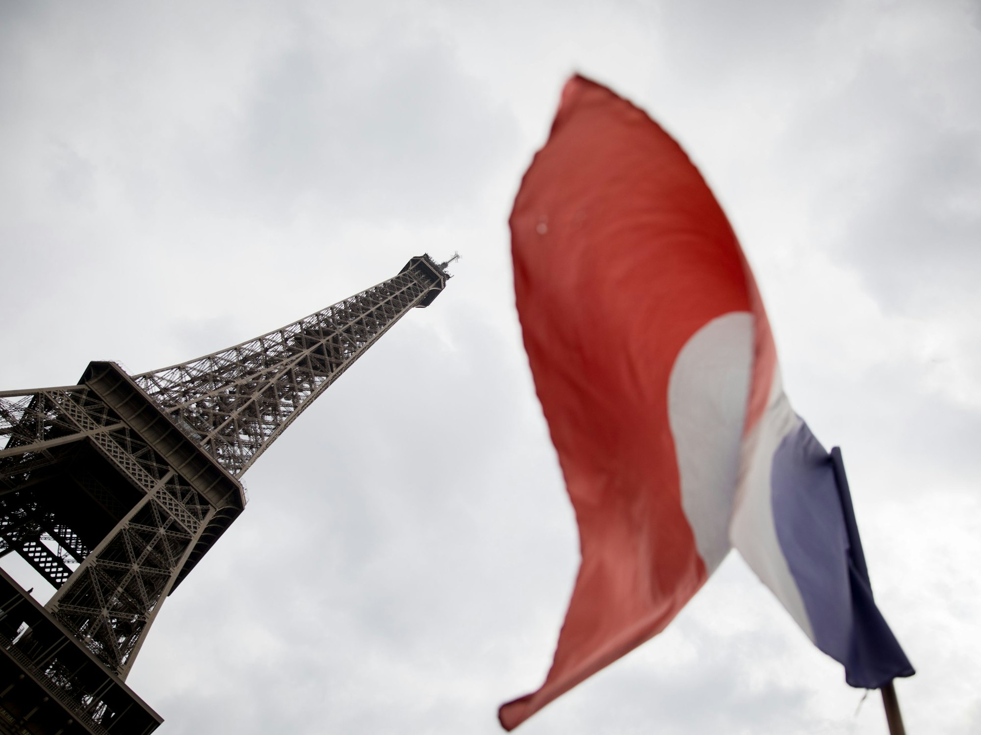 Die französische Trikolore weht vor dem Eiffelturm im Wind.