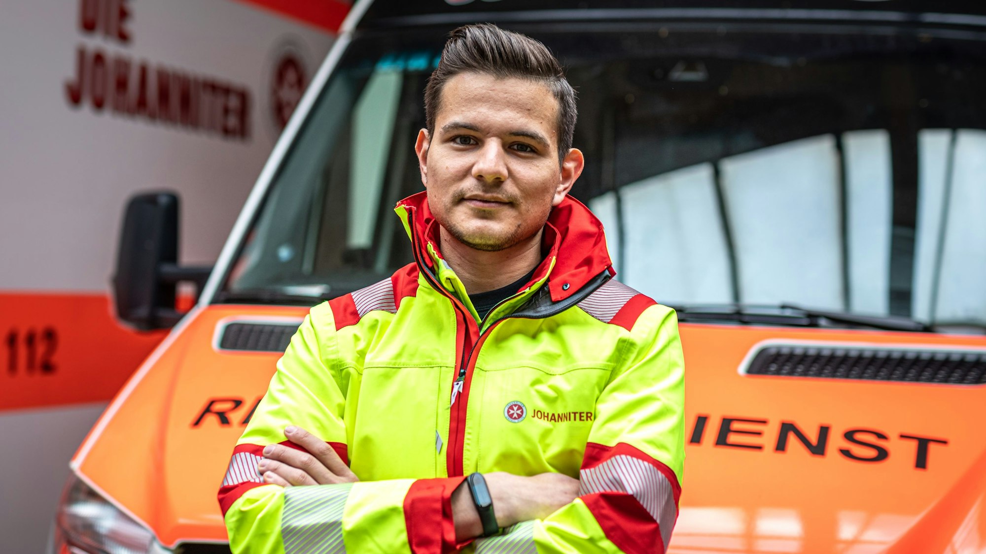 Rettungssanitäter Luis Teichmann steht vor einem Rettungswagen der Hilfsorganisation Johanniter-Unfall-Hilfe.