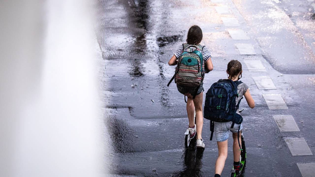 Zwei Schulkinder sind in Köln auf ihren Tretrollern unterwegs.