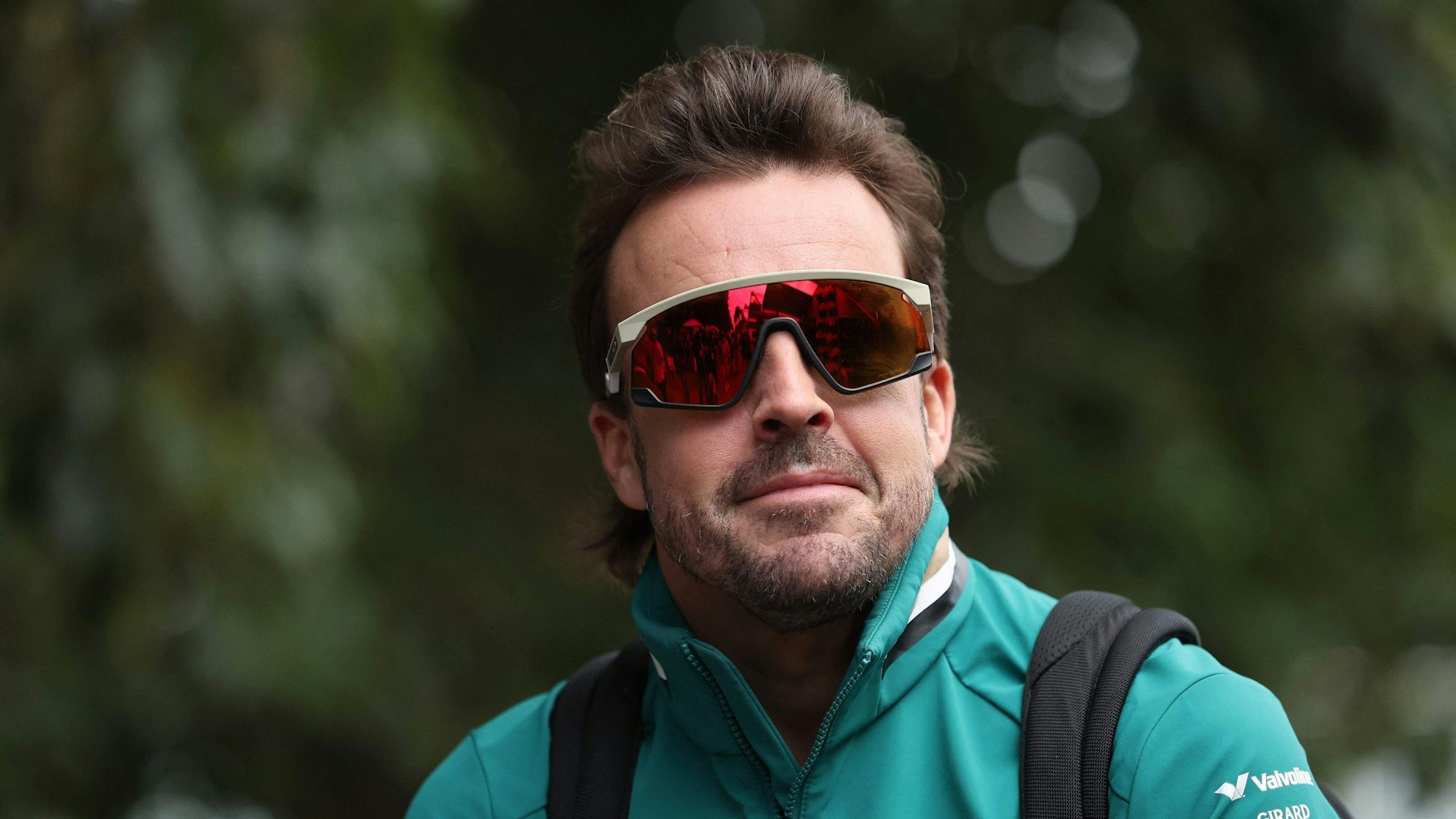 Fernando Alonso kommt mit lässiger Sonnenbrille am Fahrerlager an.
