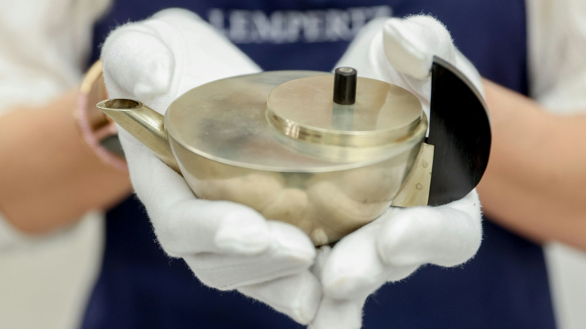 Mitarbeiterin Laura Ebert zeigt im Kunsthaus Lempertz in Köln ein wertvolles Teekännchen im Bauhaus-Stil.