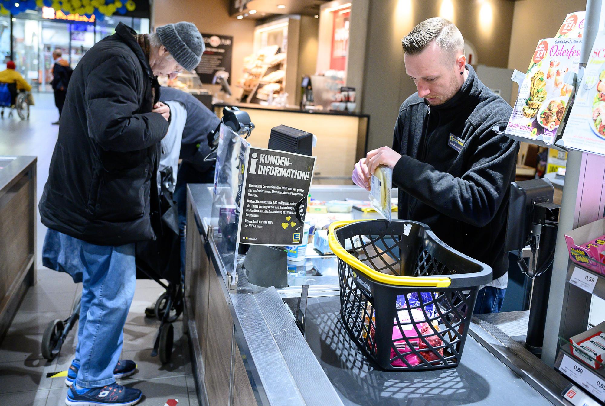 Ein Edeka-Mitarbeiter bedient in einer Filiale einen älteren Kunden.