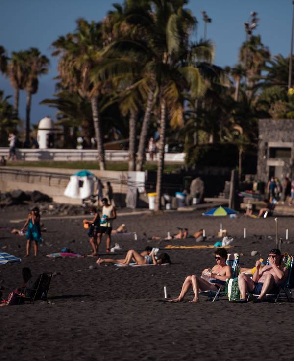 Touristinnen und Touristen sonnen sich am Playa Jardin in Santa Cruz in Teneriffa.