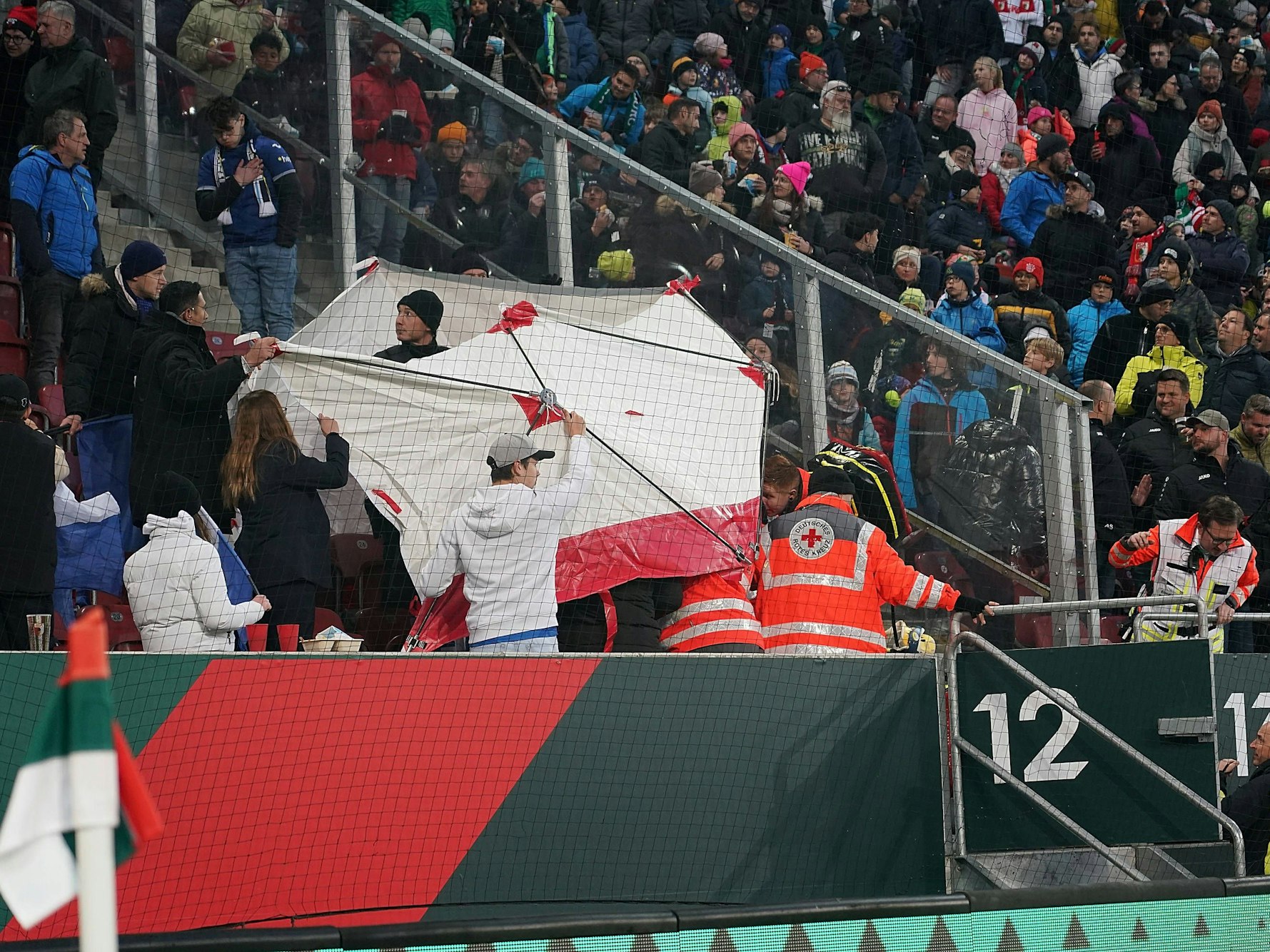 Sanitäter behandeln hinter einem Sichtschutz verletzte Personen auf der Tribüne der WWK Arena in Augsburg.