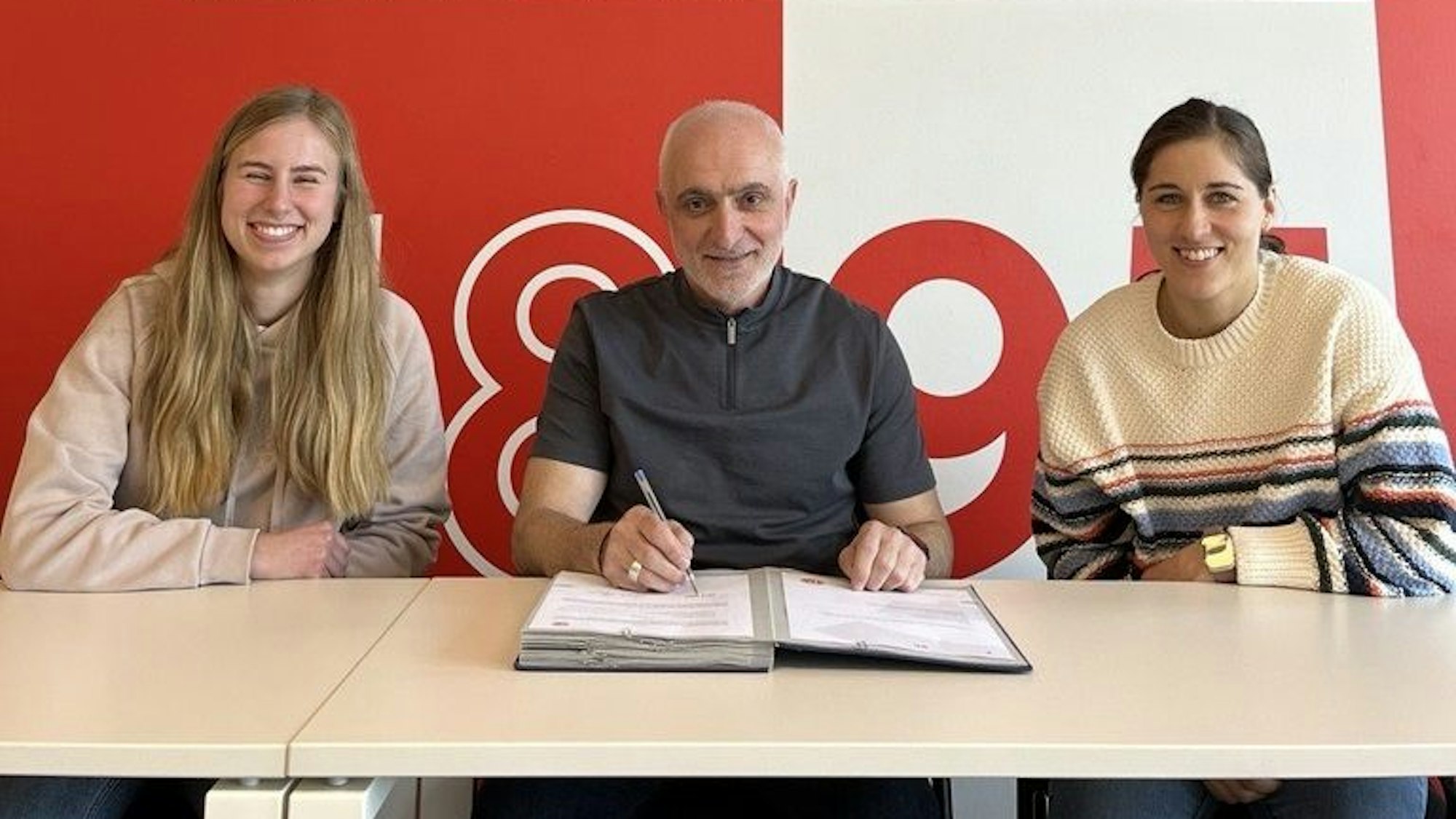 Anestis Tsentemeidis unterzeichnet seinen neuen Vertrag bei Fortuna Düsseldorf. Rechts Lisa Weiß, Sportliche Koordinatorin Mädchen- und Frauenfußball. Links die Administrative Koordinatorin der Fortuna, Lisa-Marie Peters.
