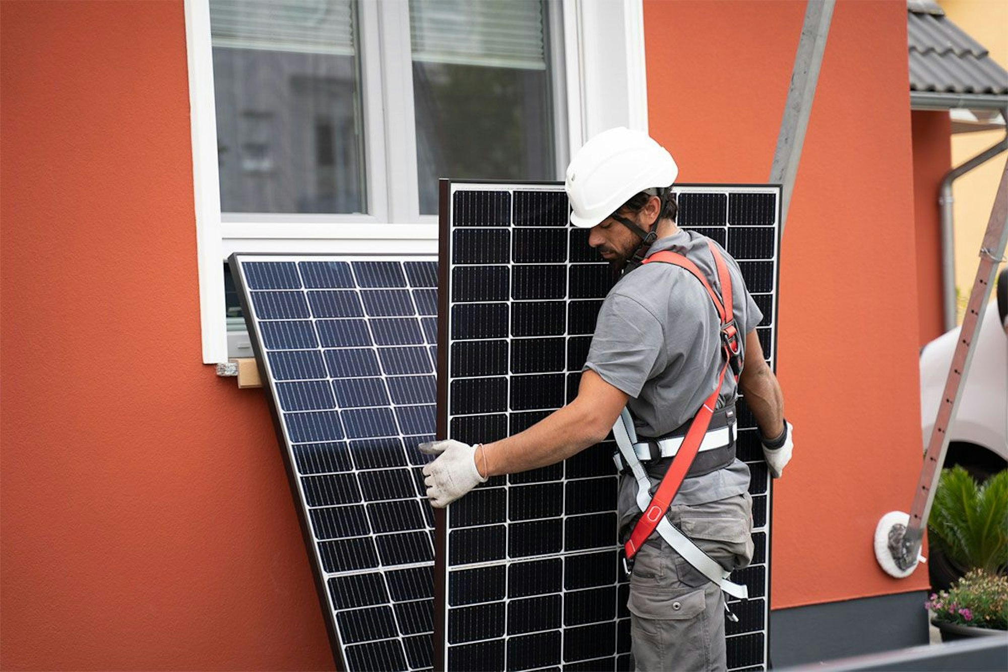 Installateur trägt Solar Modul von Enpal.