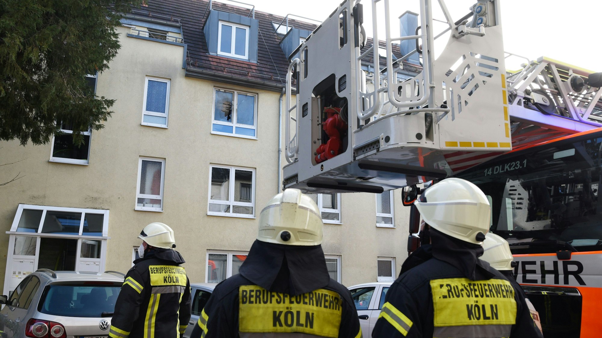 Einsatzkräfte der Feuerwehr stehen an einem brennenden Haus und überwachen die Löscharbeiten.