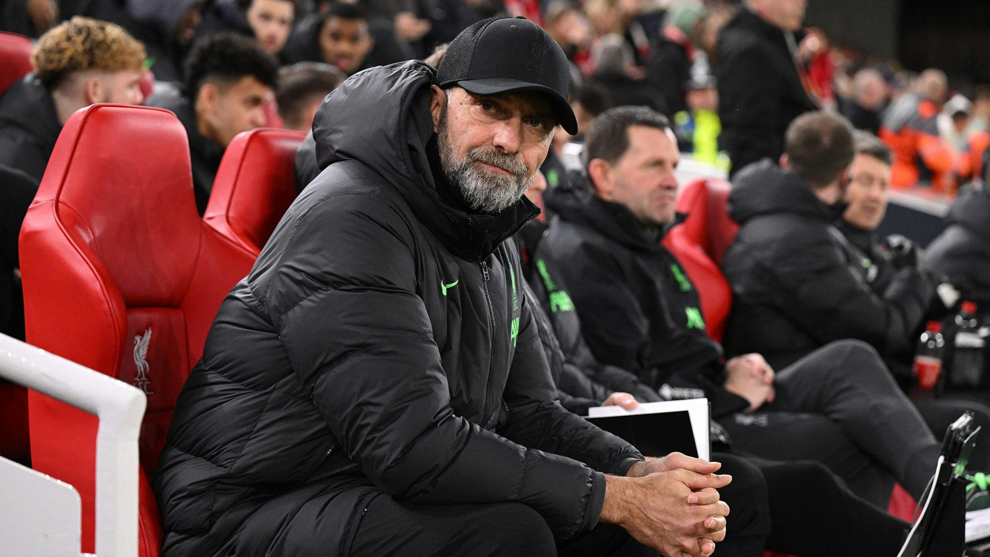 Jürgen Klopp sitzt vor einem Spiel mit Kappe auf der Trainerbank.