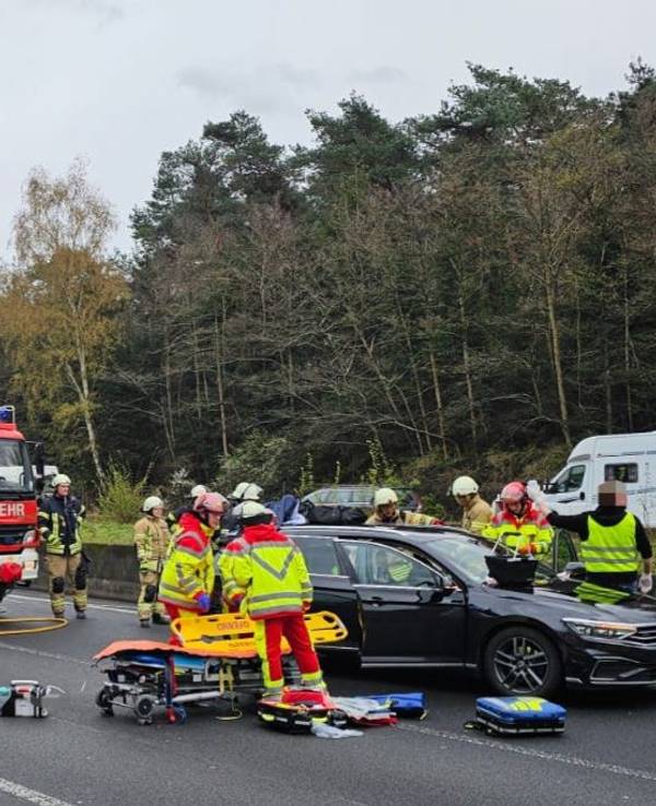 Zahlreiche Einsatzkräfte der Feuerwehr stehen an einem beschädigten Auto.