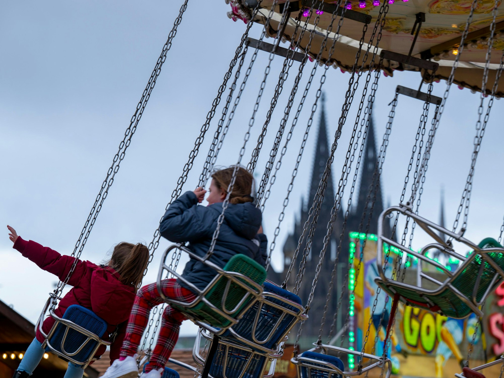 Zwei Mädchen fahren in einem Kettenkarussell.