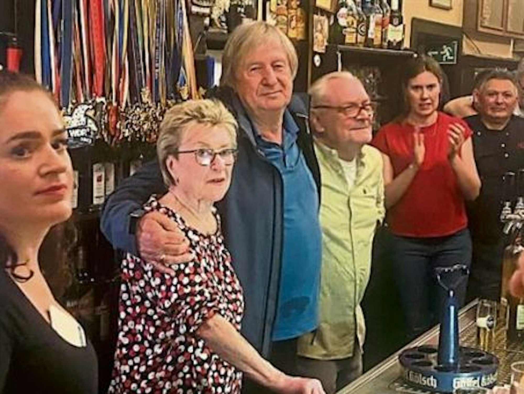 Ein Mann legt seinen Arm um eine Frau und einen Mann.