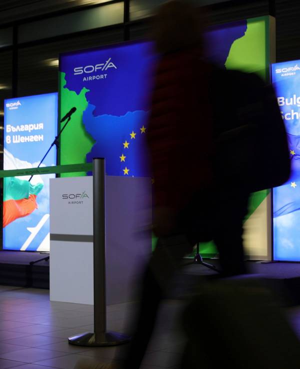 Passagiere laufen neben Plakaten, die den Beitritt Bulgariens zum Schengen-Raum auf dem Luft- und Wasserweg ankündigen.