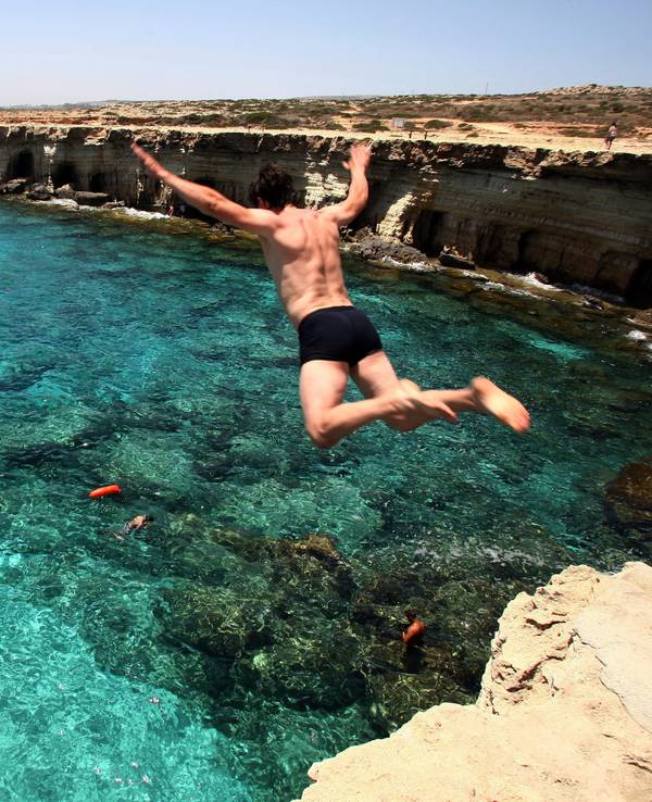 Ein Mann springt am Cape Greco auf Zypern ins Meer.