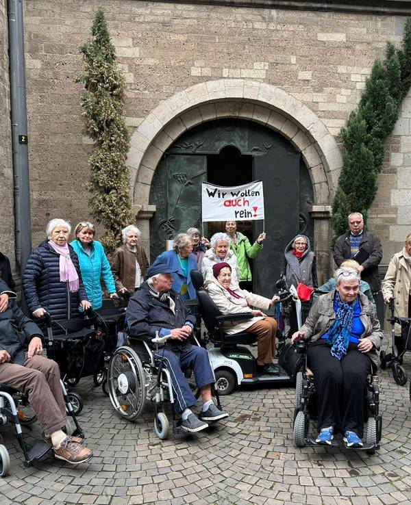 Eine Gruppe von Menschen bei einer Demo vor einer Kirche.