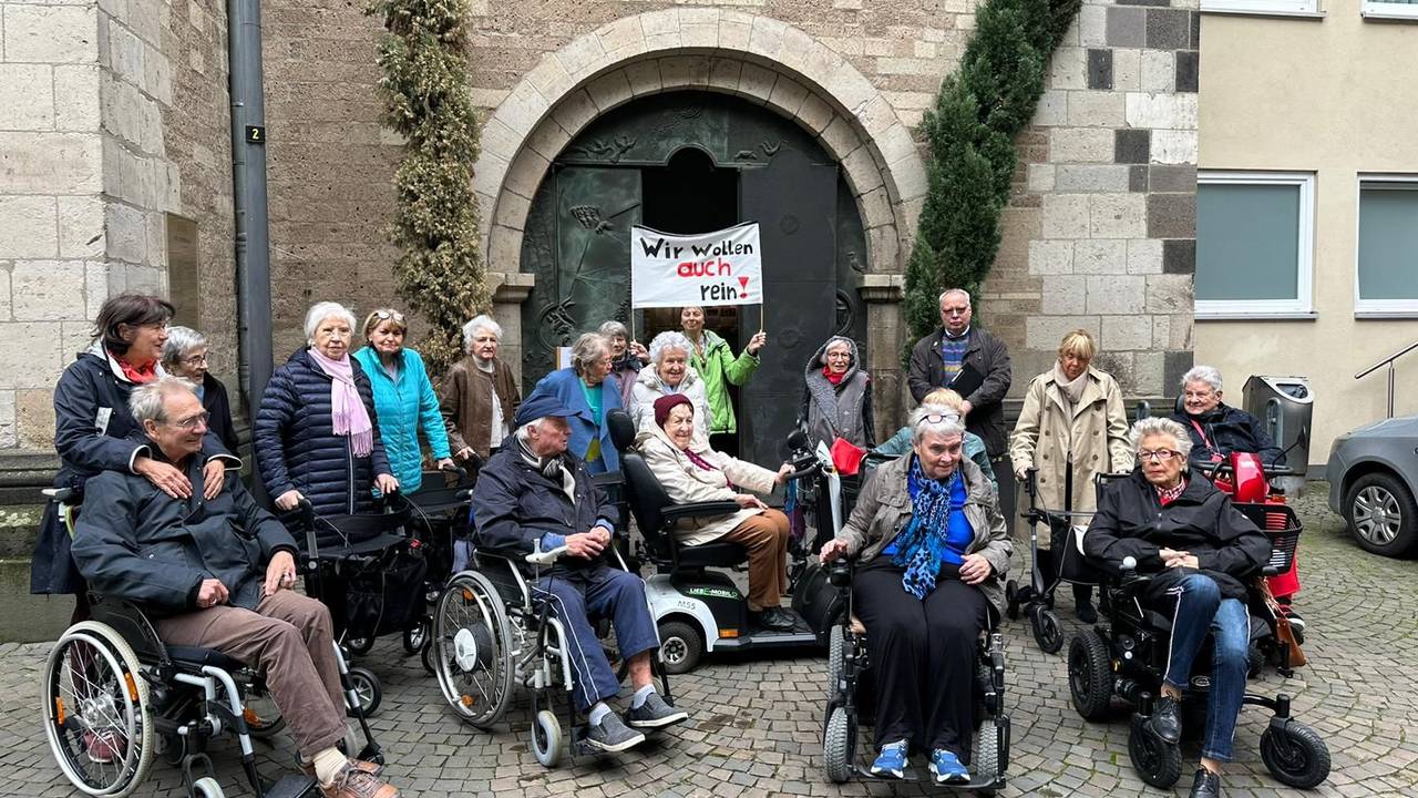 Eine Gruppe von Menschen bei einer Demo vor einer Kirche.