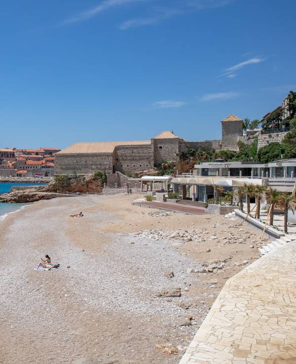 Vier Personen sonnen sich an einem Strand in Dubrovnik.