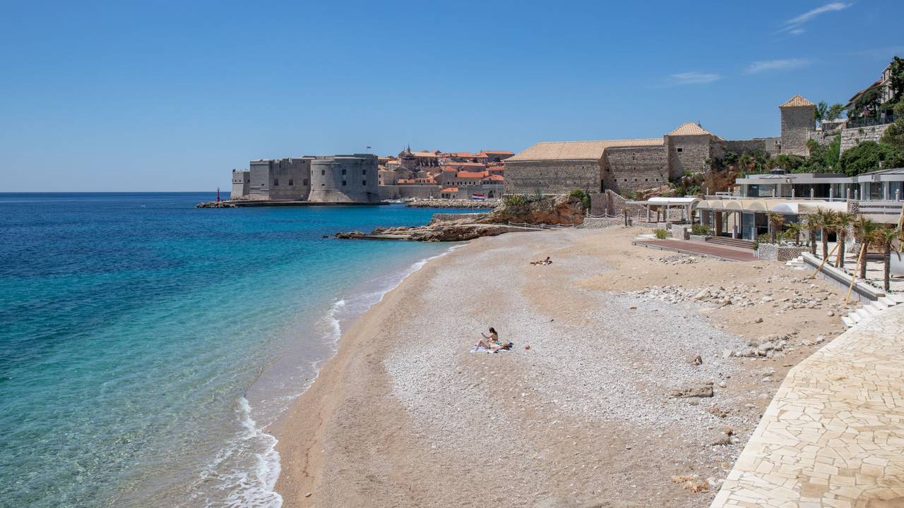Vier Personen sonnen sich an einem Strand in Dubrovnik.