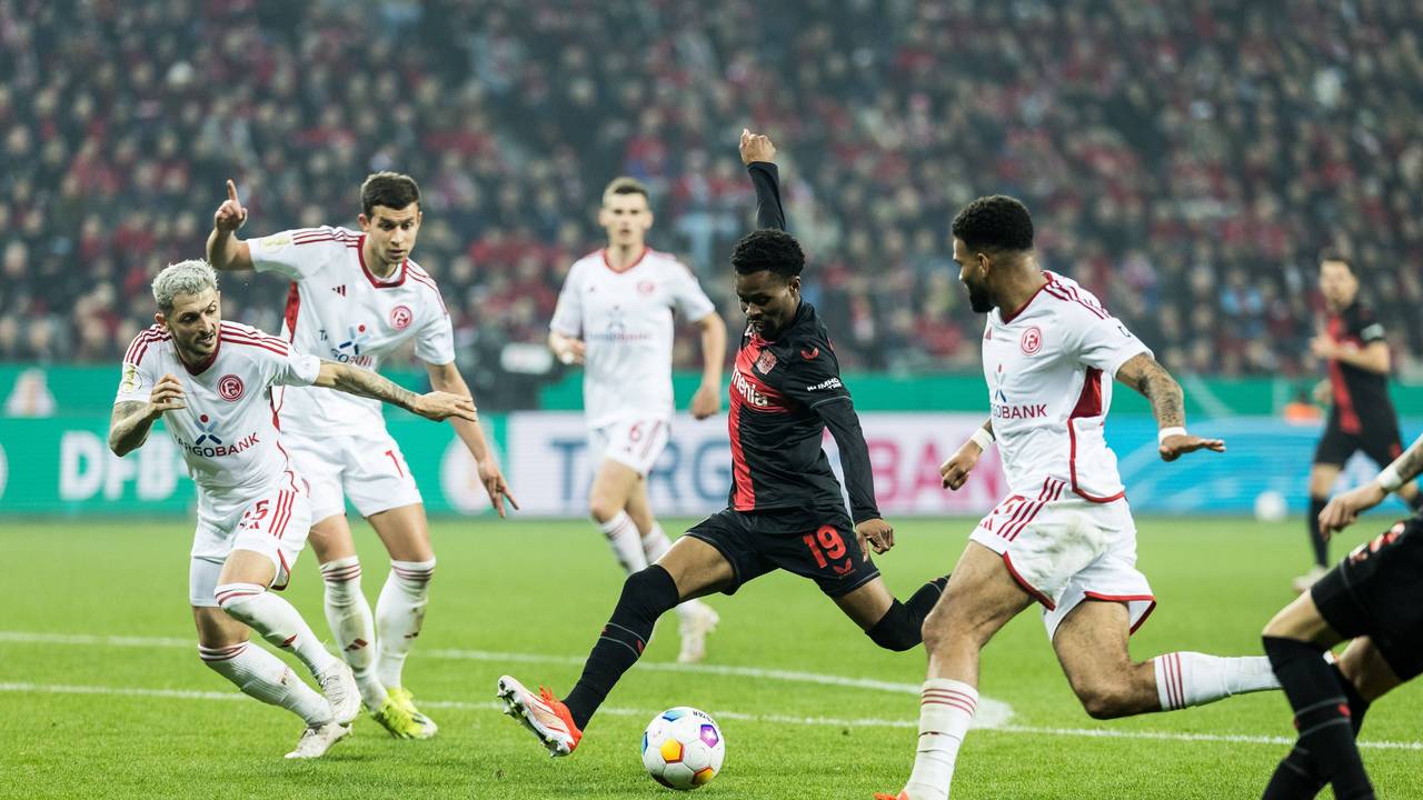 Nathan Tella schießt den Ball. Fortuna Düsseldorf Spieler stehen drumherum: Von l. n. r.: Matthias Zimmermann, Tim Oberdorf, Jamil Siebert.