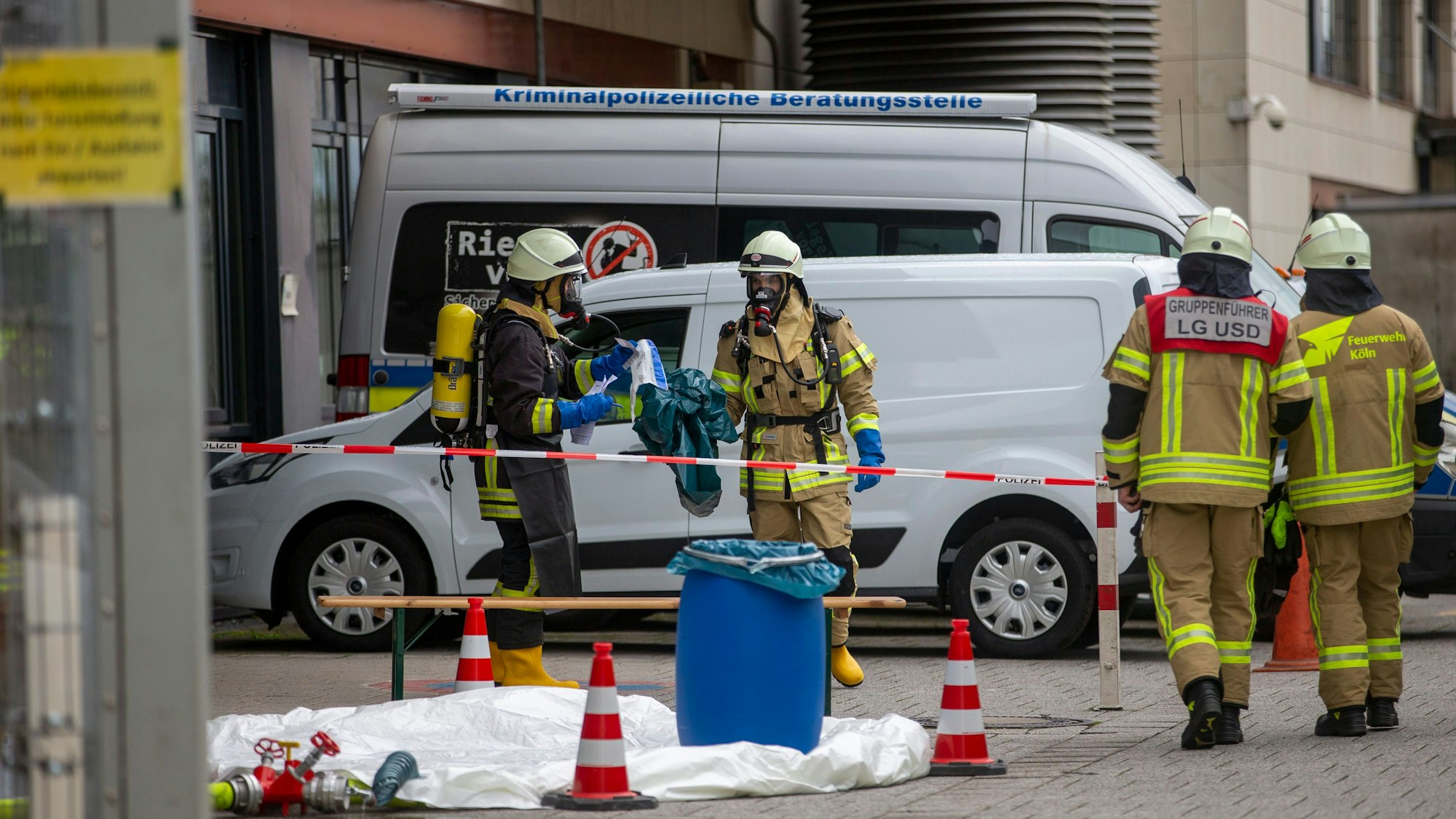Einsatzkräfte der Feuerwehr stehen in einem abgesperrten Bereich.