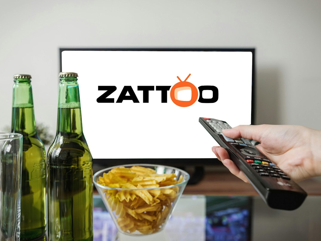 Fernseher mit Zattoo Logo. Im Vordergrund zwei Bierflaschen, eine Fernbedienung und Chips.