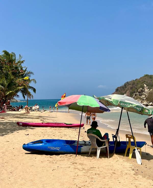 Ein Mann an einem Strand in Phuket schützt sich mit Sonnenschirmen vor der Sonne am Strand.