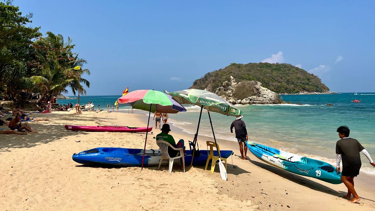 Ein Mann an einem Strand in Phuket schützt sich mit Sonnenschirmen vor der Sonne am Strand.